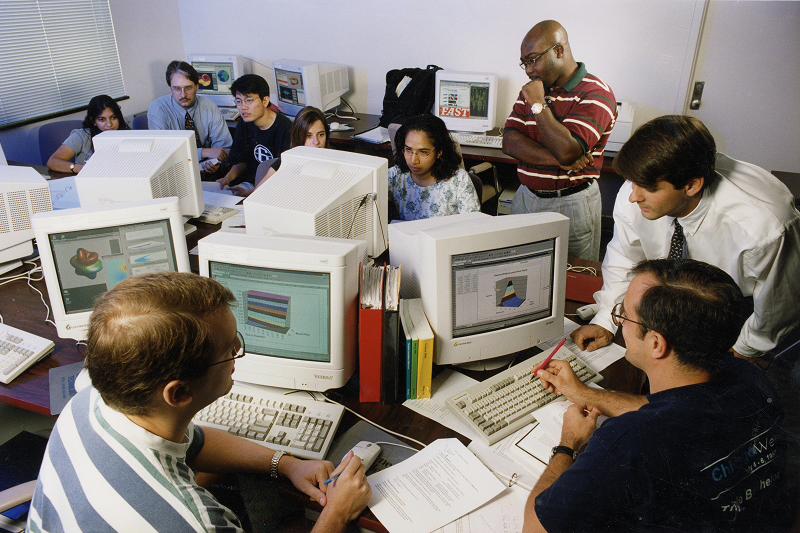 Eight students work and collaborate on early versions of computers.