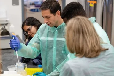 Graduate students working in a lab with a pipette and beaker